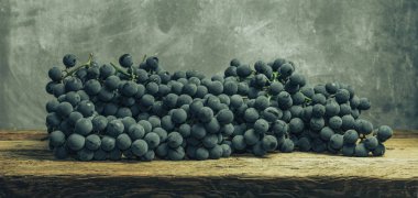 Eski bir meşe ahşap masa ve gri arka plan üzerinde güzel şarap üzüm.