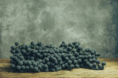 Eski bir meşe ahşap masa ve gri arka plan üzerinde güzel şarap üzüm.