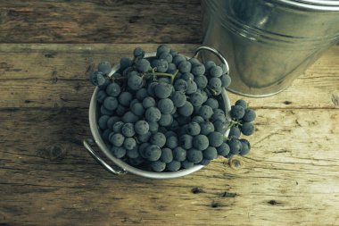 Eski bir meşe ahşap masa arka plan üzerinde gümüş sepet güzel şarap üzüm.