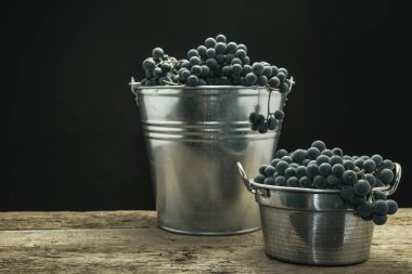 Eski bir meşe ahşap masa ve siyah arka plan üzerinde gümüş sepet güzel şarap üzüm.