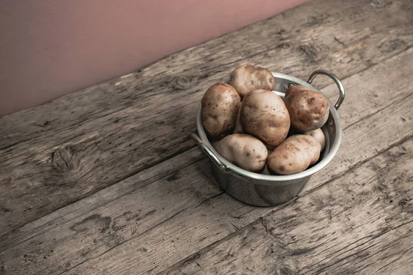 Fresh potato in silver basket on a old oak wooden table and beautiful background. Top view.