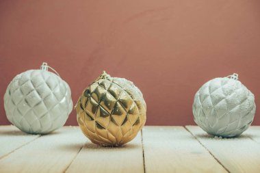 Yeni bir ahşap masada Güzel Noel baubles arkasında kar ve koyu kırmızı duvar arka plan düştü.