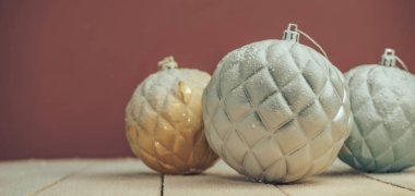 Yeni bir ahşap masada Güzel Noel baubles arkasında kar ve koyu kırmızı duvar arka plan düştü.