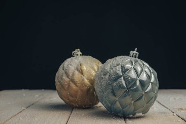 Yeni bir ahşap masada güzel Noel altın ve mavi baubles arkasında kar ve siyah arka plan düştü.