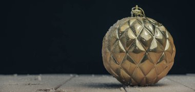 Yeni bir ahşap masada Güzel Noel altın bauble arkasında kar ve koyu kırmızı duvar arka plan düştü.