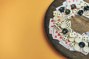 Çeşitli masa oyunları, satranç tahtaları, iskambil kağıtları, eski tahta masa turuncu arka plan dominoları..