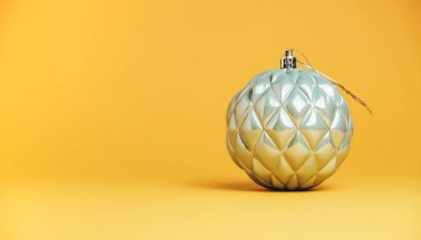 Güzel, gümüş bir Noel topu. Sarı bir arka plana yakın..