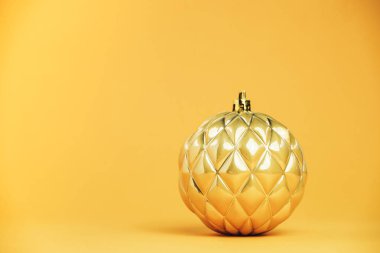 Güzel bir Noel altın topu, sarı bir arka plana yakın..