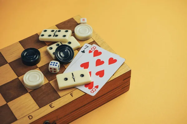 Various Board Games Chess Board Playing Cards Dominoes Orange Background — Stock Photo, Image