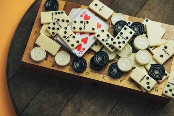 Çeşitli masa oyunları, satranç tahtası, eski tahta bir arka planda domino taşları..
