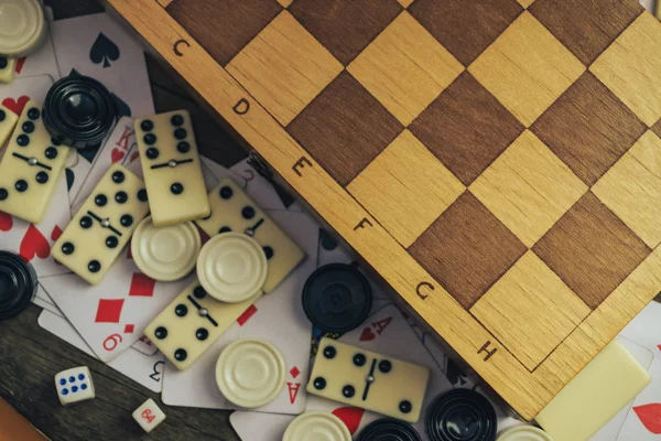 Çeşitli masa oyunları, satranç tahtası, eski tahta bir arka planda domino taşları..