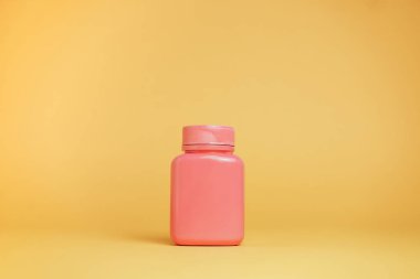 Sarı arka planda haplar için pembe şişe..