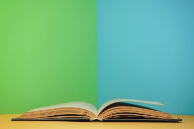 Sarı masa ve mavi duvar arkaplanı üzerinde açık güzel bir kitap..