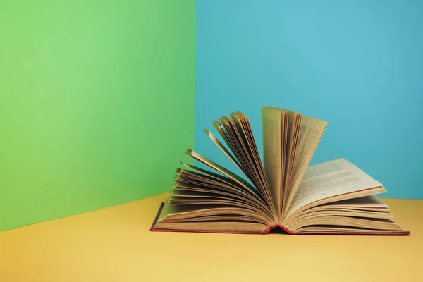 Beautiful open red book on a yellow table and green blue background.