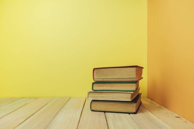 Ahşap bir masada güzel bir kitap ve sarı turuncu bir arka plan..