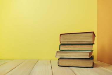 Ahşap bir masada güzel bir kitap ve sarı turuncu bir arka plan..