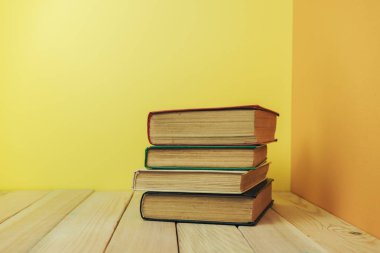 Ahşap bir masada güzel bir kitap ve sarı turuncu bir arka plan..