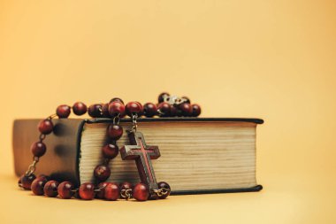 Sarı arkaplan masasında eski boncukları olan kutsal İncil. Din kavramı.