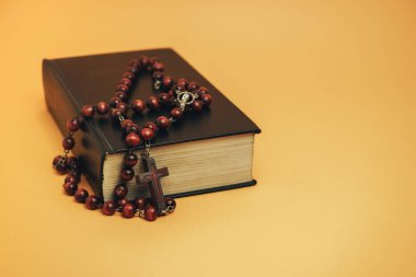 Sarı arkaplan masasında eski boncukları olan kutsal İncil. Din kavramı.