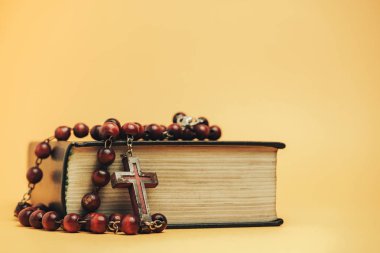 Sarı arkaplan masasında eski boncukları olan kutsal İncil. Din kavramı.