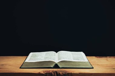 Open Holy Bible on a red old wooden table. Beautiful Black wall background.	