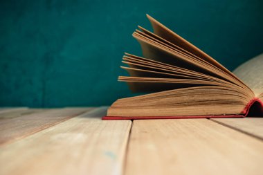 Kırmızı ahşap bir masa ve koyu yeşil bir arka plan üzerinde eski ve güzel bir kitap..