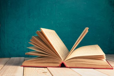 Kırmızı ahşap bir masa ve koyu yeşil bir arka plan üzerinde eski ve güzel bir kitap..