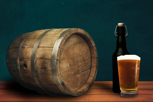 Beautiful wooden barrel on a red wood table and beer of glass,  green  wall background.