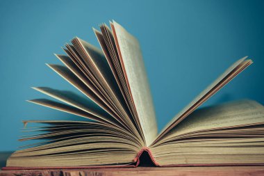 Kırmızı ahşap masa ve mavi duvar arka planında güzel, açık bir kitap..