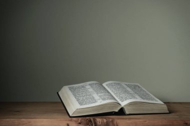 Kırmızı ahşap bir masa ve beyaz duvar arka planında kutsal kitabı aç. Din kavramı.