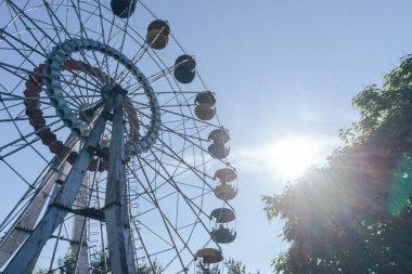 Mavi gökyüzü ve günbatımı arka planındaki lunaparkın güzel renkli dönme dolabı.