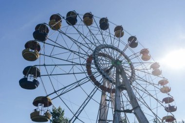 Mavi gökyüzü ve günbatımı arka planındaki lunaparkın güzel renkli dönme dolabı.