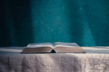 Open Holy Bible on a old table. Beautiful green wall background.	