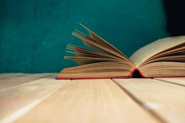 Kırmızı ahşap bir masa ve koyu yeşil bir arka plan üzerinde eski ve güzel bir kitap..