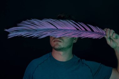 Genç adam yüzünü neon ışıkla kaplamış. Siyah üzerine. Minimalizm retro tarzı konsept.