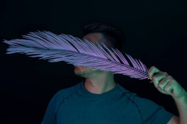 Genç adam yüzünü neon ışıkla kaplamış. Siyah üzerine. Minimalizm retro tarzı konsept.