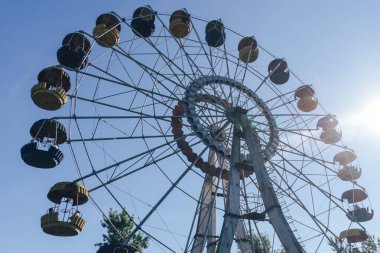 Mavi gökyüzü ve günbatımı arka planındaki lunaparkın güzel renkli dönme dolabı.