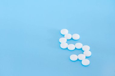 Bir dolar şekillendirme dökülüp beyaz hap mavi bir arka plan üzerinde oturum.