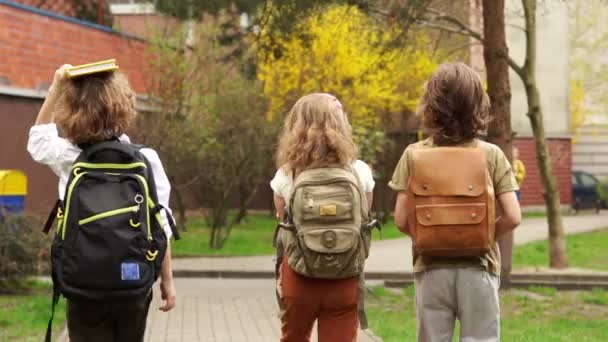 Schüler kehren von der Schule zurück. zurück zur Schule. Drei Kinder, zwei Jungen und ein Mädchen, Klassenkameraden. Schulpause — Stockvideo