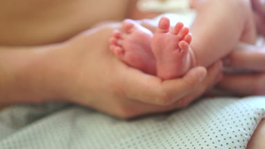 Çocuk babasının ellerinde yatıyor. Yeni doğan bebeği önleyici masaj yapıyor baba. Çocuk koruma