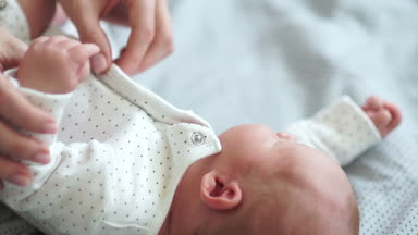 Genç bir anne onun yeni doğan bebek undresses, onu yavaşça öper. Anne bakımı, anne ve bebek