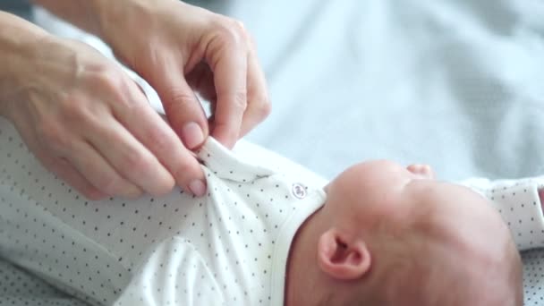 Moeder haar pasgeboren baby jurken, hem zachtjes te kussen. Moeders zorg, moeder en baby — Stockvideo