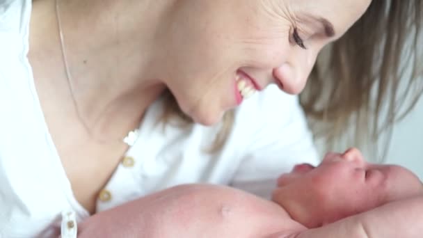 Un bebé recién nacido bosteza en los brazos de su madre. Mamá le sonríe a su bebé. Día de las Madres — Vídeos de Stock