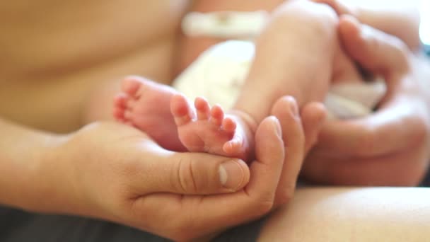 Contact met de huid op de huid. Een jonge vader houdt de benen van een pasgeboren baby. Gelukkig vaderschap. Fathers Day — Stockvideo