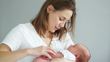 Orta yaşlı bir kadın yavaşça elini tutarak onun yeni doğan bebek sallanır. Taşıyıcı annelik. İn vitro fertilizasyon