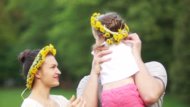 Şirin komik küçük 3 yaşındaki kızı hugs ve öper annesi ve babası açık. Mutlu aile bahar doğa şehir yeşil park sahiptir. Mutlu aile tatil
