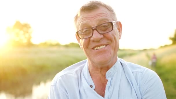 Un pensionato spensierato che sorride guardando la telecamera. Ritratto di un uomo anziano con gli occhiali. Buone feste. Festa dei Padri — Video Stock