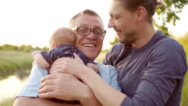 En lycklig ung man kramar sin far och sin nyfödde son. Fäder kärlek. kontinuiteten i generationer. Manliga ömhet. Fars dag — Stockvideo