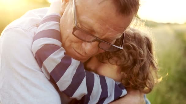 Portrait rapproché d'un homme mature embrassant son défunt fils. Bonne paternité. Enfant bouclé, un homme portant des lunettes optiques. Coucher de soleil coloré — Video