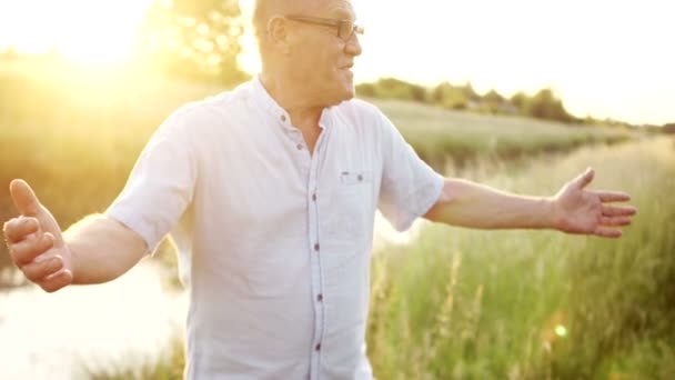 Der Enkel greift auf seinen Großvater zurück. freudiges Treffen am Ufer des Flusses. Familienwochenende. farbenfroher Sonnenuntergang — Stockvideo